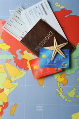 Fototapeta premium Karty kredytowe z paszportami i biletami na wakacje na tle mapy świata
