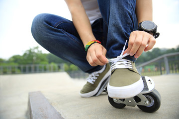 Obraz premium freeline skateboarder tying shoelace at skatepark ramp