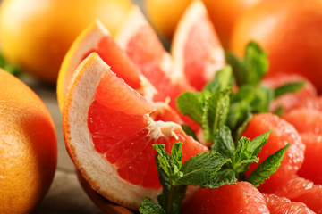 Sliced grapefruits with mint on wooden background, close up