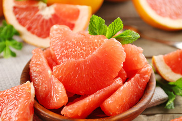 Juicy grapefruit pieces with fresh mint in a bowl, close up