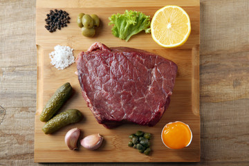 Beef tartare ingredients on wooden cutting board