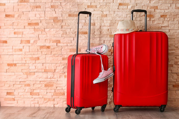 Red suitcases with hat and gumshoes on brick wall background