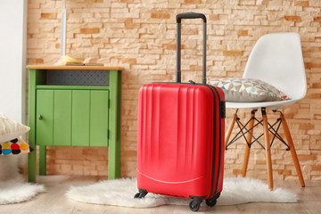 Fototapeta na wymiar Red suitcase, nightstand and chair indoors