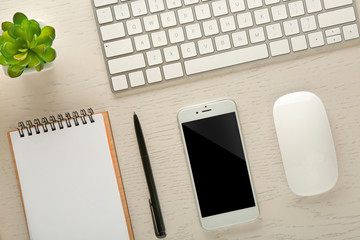 Workplace with mobile phone, peripheral devices and stationery on light table