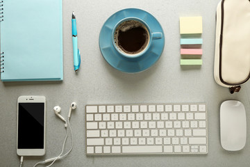 Workplace with mobile phone, peripheral devices and stationery on grey table