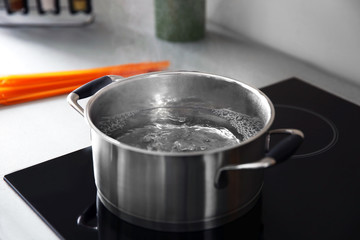 Boiling water in pan on electric stove in the kitchen