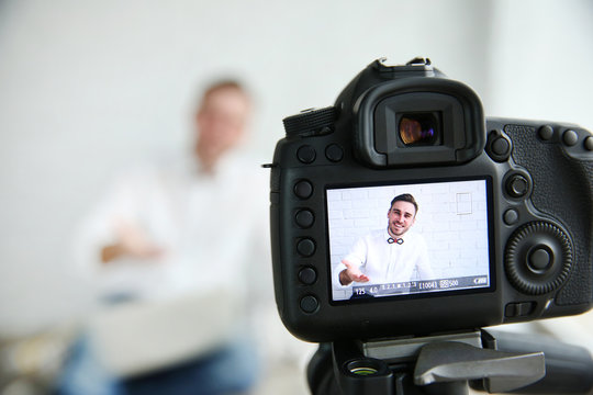Young male blogger on camera screen