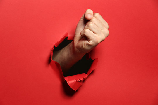 Male Fist Punching Through Red Paper