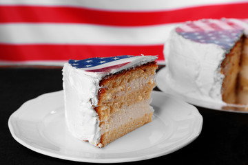 Piece of American flag cake, on black wooden background.