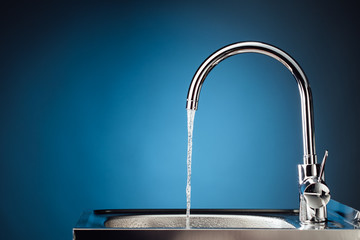 robinet mélangeur avec eau qui coule, fond bleu