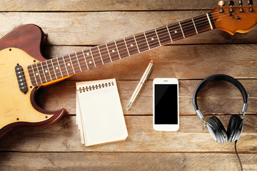 Guitar and smartphone on wooden background
