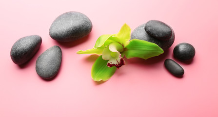 Spa stones and yellow orchid on pink background