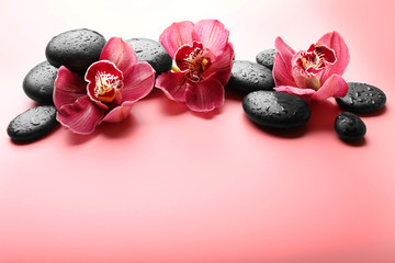 Spa stones and red orchid on pink background