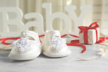 Beautiful composition with baby booties and gift box on wooden background