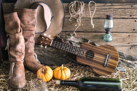 ukulele with american west rodeo brown cowboy hat and leather boots in vintage ranch barn studio background, Still life style