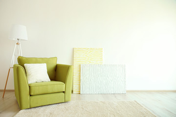 Green armchair and lamp on light wall background