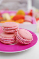 Fresh macaroons on pink plate, closeup