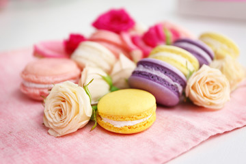 Fresh macaroons and roses on pink napkin, closeup