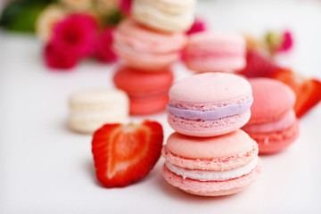 Macaroons with roses and strawberries on white background