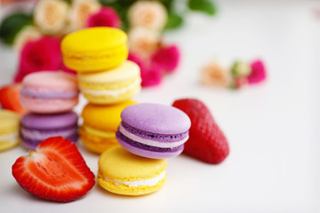Macaroons with roses and strawberries on white background