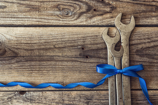 Bunch of wrenches with a blue ribbon on a rustic wooden backgrou