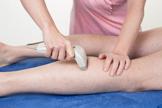 Laser hair removal on man legs at beauty center