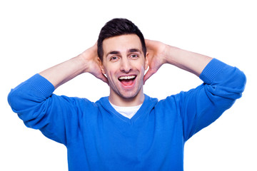 What a surprise! Surprised young man in casual wear holding hands behind head and smiling while standing isolated on white background