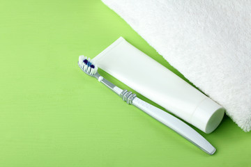 toothbrush with toothpaste near bath towels on green background