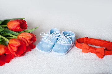 red tulips tie and children blue boots on  white background