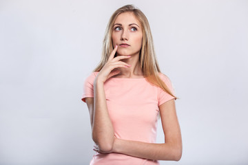 Lost in thoughts. Thoughtful young blond hair woman holding hand on chin and looking away while...