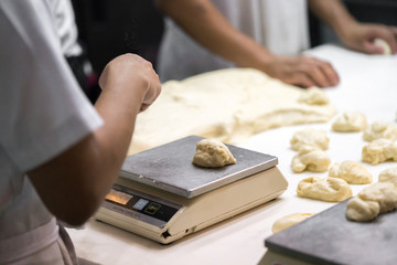 Hands baking dough with rolling pin on wooden table, depth of field
