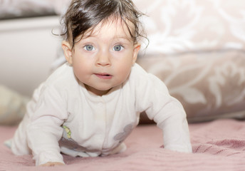 Fototapeta premium Portrait of little girl close up. Six-months old child lying on her stomach and tries to lift. Girl with different funny emotions. 