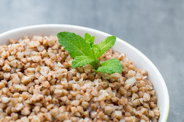 Buckwheat porridge in a bowl with mint leaves and blueberries.