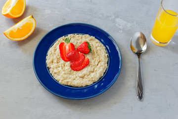 Oatmeal porridge with strawberries and glass of orange juice