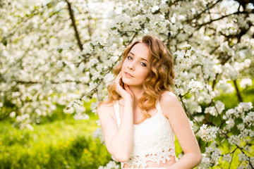Fototapeta na wymiar Spring beautiful girl, blonde, standing in a blooming Apple orchard .