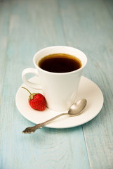 A cup with a drink and a strawberry on a blue