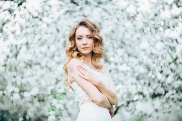 Fototapeta na wymiar Spring beautiful girl, blonde, standing in a blooming Apple orchard .