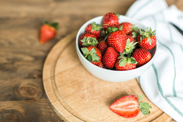 ripe strawberries on plate on wooden background