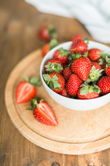 ripe strawberries on plate on wooden background