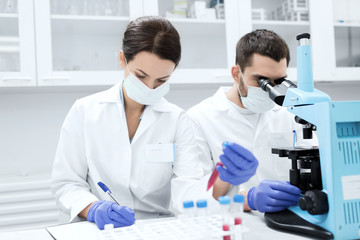 scientists with clipboard and microscope in lab
