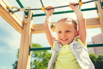 Fototapeta premium happy little girl climbing on children playground