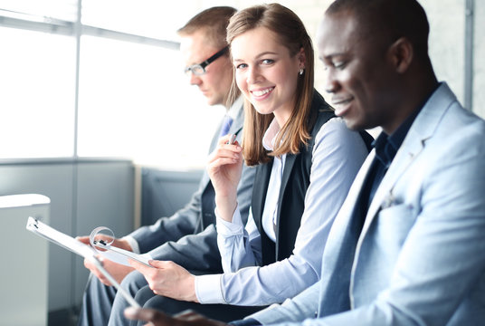 Smiling businesswoman looking at camera at seminar with her colleagues near by