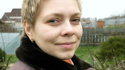 Country blond short hair girl portrait outdoors in the vegetable kitchen garden outside the house. Country rural scene.