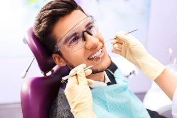 Portrait of male. smile face. Dental care Concept. Dental inspection is being given to Beautiful man surrounded by dentist and his assistant

