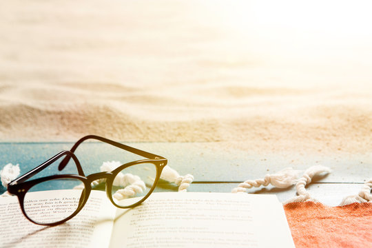 Buch und Brille an einem Sandstrand