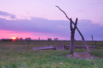 antiker Ziehbrunnen auf dem Lande zum Sonnenuntergang
