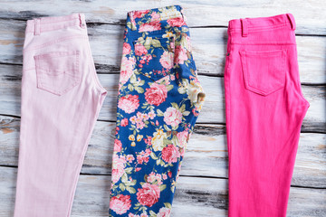 Light pink and floral pants. Girl's trousers on wooden background. Colorful summer garments. Quality cotton and stylish print.