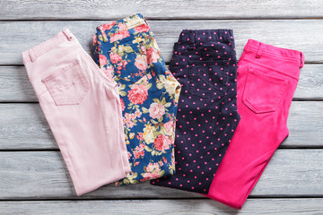 Colorful female pants. Bright and dark folded trousers. Last items on shop showcase. What to wear this spring.