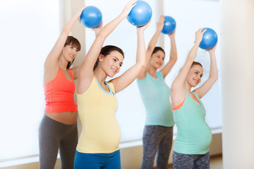 happy pregnant women exercising with ball in gym
