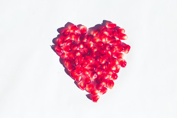 heart of vibrant pomegranate on white background, minimal pop concept